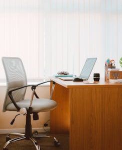 A tranquil modern home office featuring a wooden desk, ergonomic chair, and soft natural light.