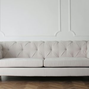 Luxurious white sofa in a modern minimalist interior with wooden flooring.