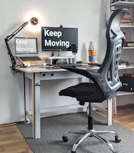 Stylish home office with ergonomic chair, desk, laptop, and motivational screens.